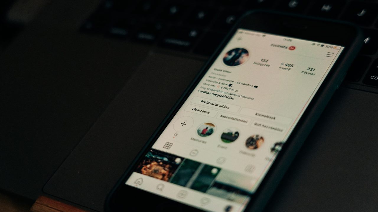 Smartphone social profile beside laptop representing Facebook pages and websites